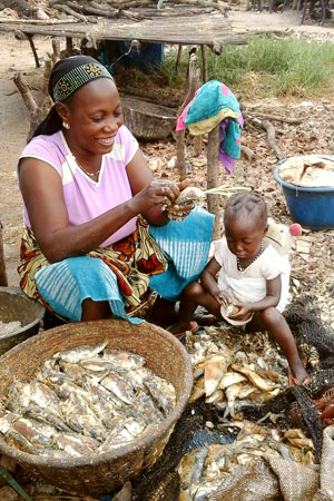 Mother and daughter removing fish scales and peeling off skins in Kafountine. Women have to bring their kids onsite because there are no daycares.