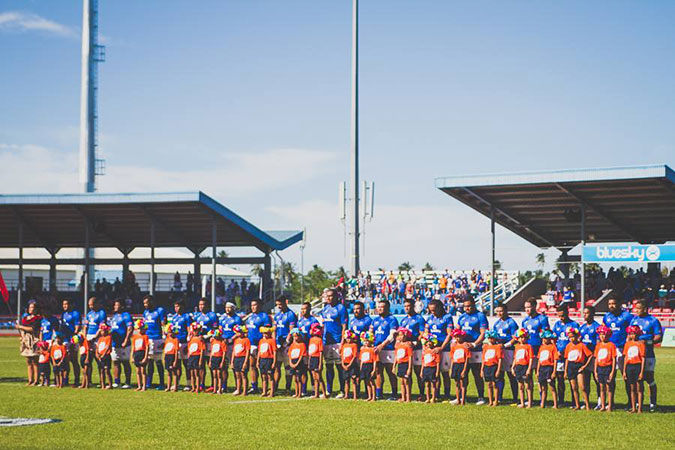 Manu Samoa players and school children during the singing of the national anthem on 25 June, wearing orange bands to show their support for ending violence against women. UN Women/Ken Tai Tin