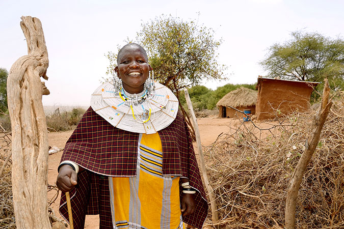 Mama Neema stands at the entrance of her traditional boma (homestead) where she built three houses for her family in Kimokouwa village in Arusha, Tanzania. Photo: UN Women/Deepika Nath