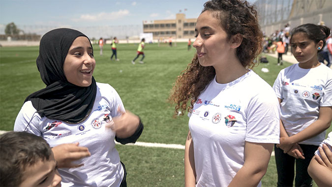 Syrian refugees and Jordanian girls build positive relationships during a mixed-nationality football camp in Jordan. Photo: UN Women/Christopher Herwig