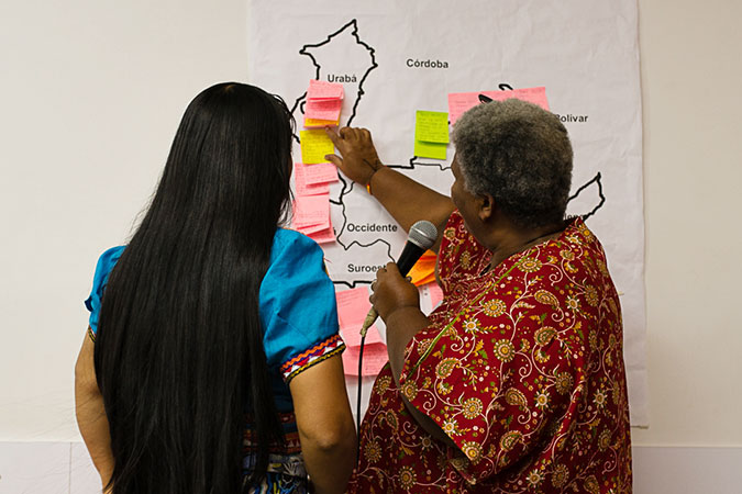 Two women leaders look at a map while discussing how to support peace strategies in various communities. Photo: David Fayad