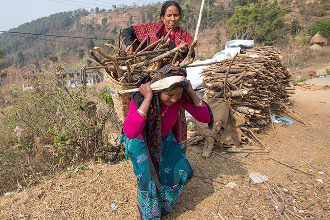 Laxmi Biswokarma, 39, is walking towards her house with a small load of firewood on her back. Photo: UN Women/Narendra Shrestha