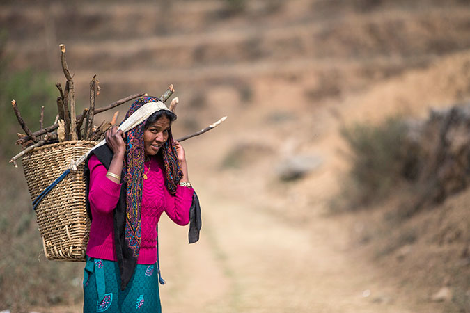 Laxmi Biswokarma, 39, is walking towards her house with a small load of firewood on her back. Photo: UN Women/Narendra Shrestha
