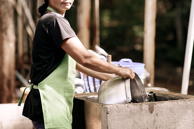Una trabajadora migrante lava ollas en Bangkok, Tailandia. Foto: ONU Mujeres/Pornvit Visitoran.