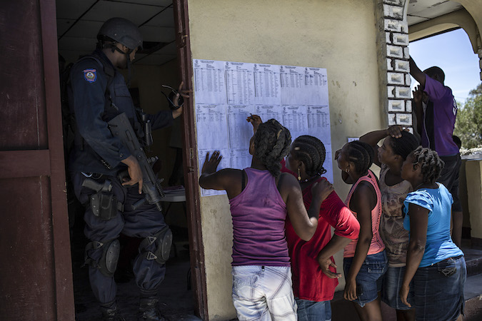 Residents of II de la Gonave, Haiti, look for their names on the eligible electors list at the Community Electoral Office. Photo: UN Photo: Logan Abassi