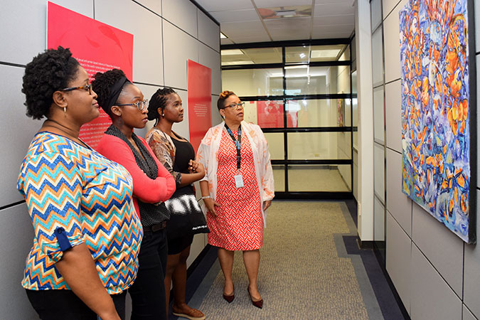 UN Women Representative M. Alison McLean (at right) and UN Women MCO staff viewing one of the artworks at the 1 in 3 Art Exhibition held at the UN Women Multi Country Office (MCO) in Christchurch, Barbados. Photo: UN Women/Sharon Carter-Burke