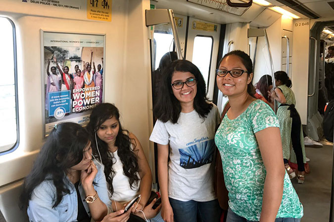 Passengers on Delhi Metro pose in front of women's empowerment campaign poster. Photo: UN Women/Vandinika Shukla