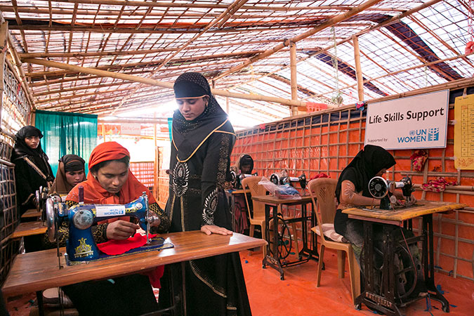 After eight days of training, Somjida, 15 (standing), completed her first clothing item, a red blouse, at a UN Women-supported Action Aid Women Friendly Space in Balukhali Rohingya Refugee camp. Photo: UN Women/Allison Joyce