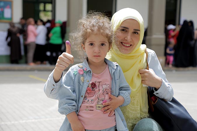 A woman shows off the electoral ink after voting in the parliamentary elections in Lebanon, with her daughter. Photo: UN Women/Jean Safi