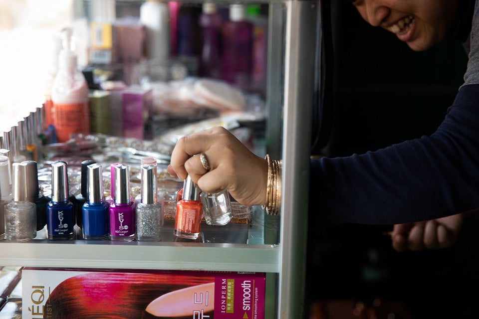 Kunthea smiles as she reaches for her rainbow-colored nail polish collection. Photo: UN Women/Stephanie Simcox