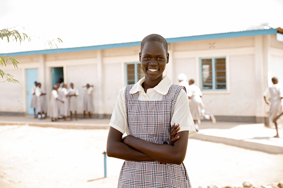 Nyamam Gai Gatluak stands outside of classrooms at the Angelina Jolie Primary School. Photo: UN Women/Ryan Brown