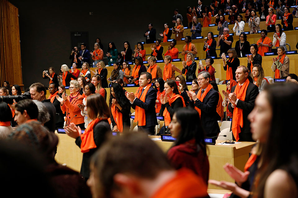 Audience members in orange scarves applaud panel speaker Ajna Jusic during the official UN commemoration of the International Day for the Elimination of Violence against Women took place on 25 November in the ECOSOC chamber of UN Headquarters in New York. Photo: UN Women/Ryan Brown