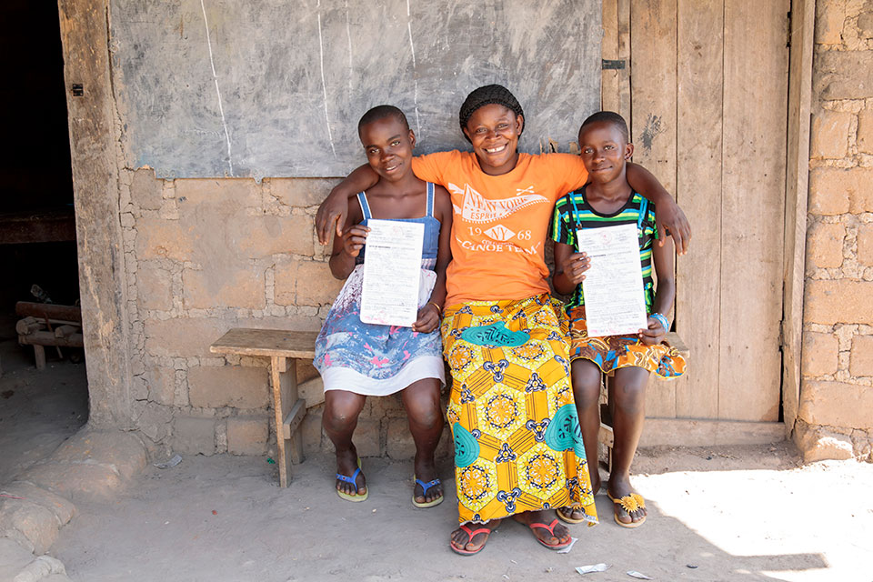 Elizabeth, 13, at left, Yeng, 12, at right, and Vivian, Yeng’s mother, center, display the newly acquired birth certificates which open the door for the girls to attend school, sit for national exams and apply for national ID. Photo: UN Women/Ryan Brown