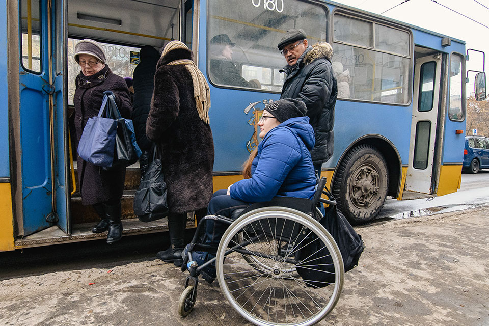 Tetyana Bobrovska  waits for a city bus in Kramatorsk, Ukraine.  In Kramatorsk, despite recent improvements in infrastructure, many older buses and bus stop shelters are inaccessible to wheelchair users.   Photo: UN Women/Artem Hetman