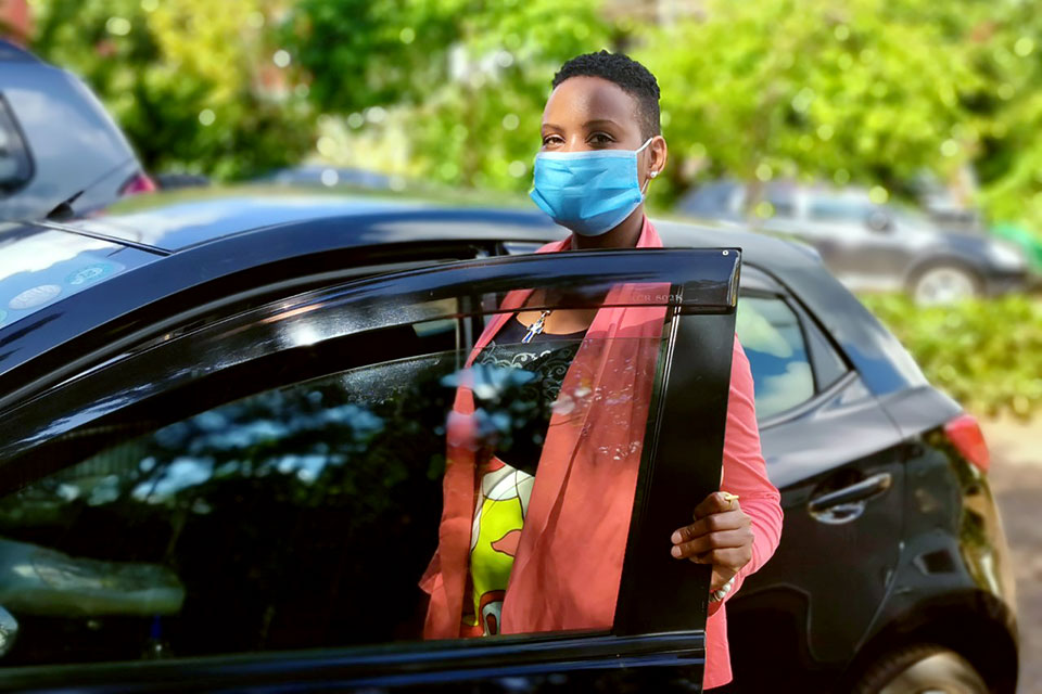 Esther Macharia poses with her car, while wearing a face mask. Photo: UN Women/Alpha Ba