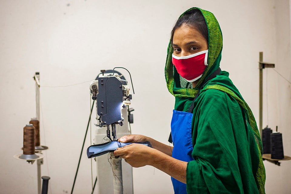 Riya Akter, 22, is an apparel worker, just like her husband. Asked if she was afraid of becoming infected with coronavirus, she said work came first and needed to be done, otherwise there would not be food on the table.  She works while maintaining social distance with other workers as ready made garment (RMG) factories reopened amid the Covid-19 pandemic in Dhaka, Bangladesh.  May 2020. Photo: UN Women/Fahad Abdullah Kaizer