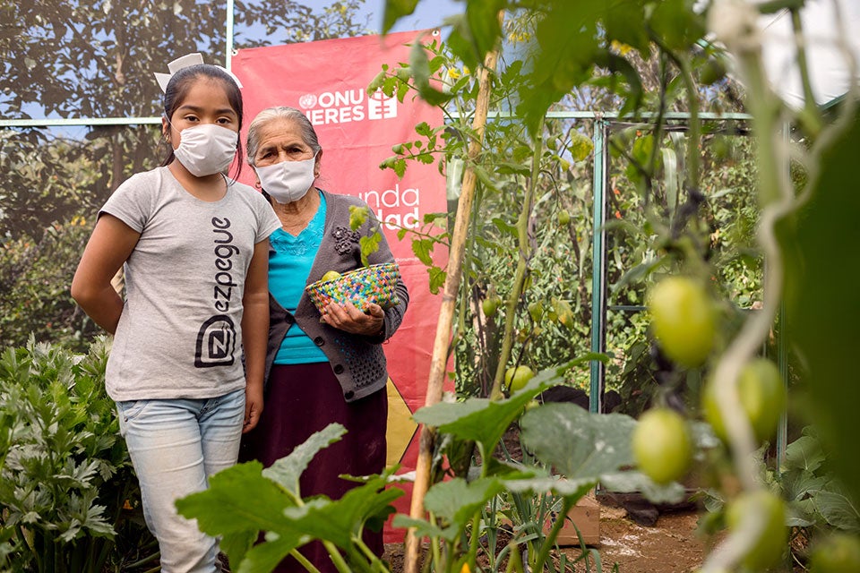 In Ajalpan, Anayeli, 11, and Sirenia Alva Altamira, 80, stand for a photo with produce from the greenhouse they tend. With children out of school due to the coronavirus pandemic, some program participants bring children along to learn too. Photo: UN Women/ Dzilam Méndez