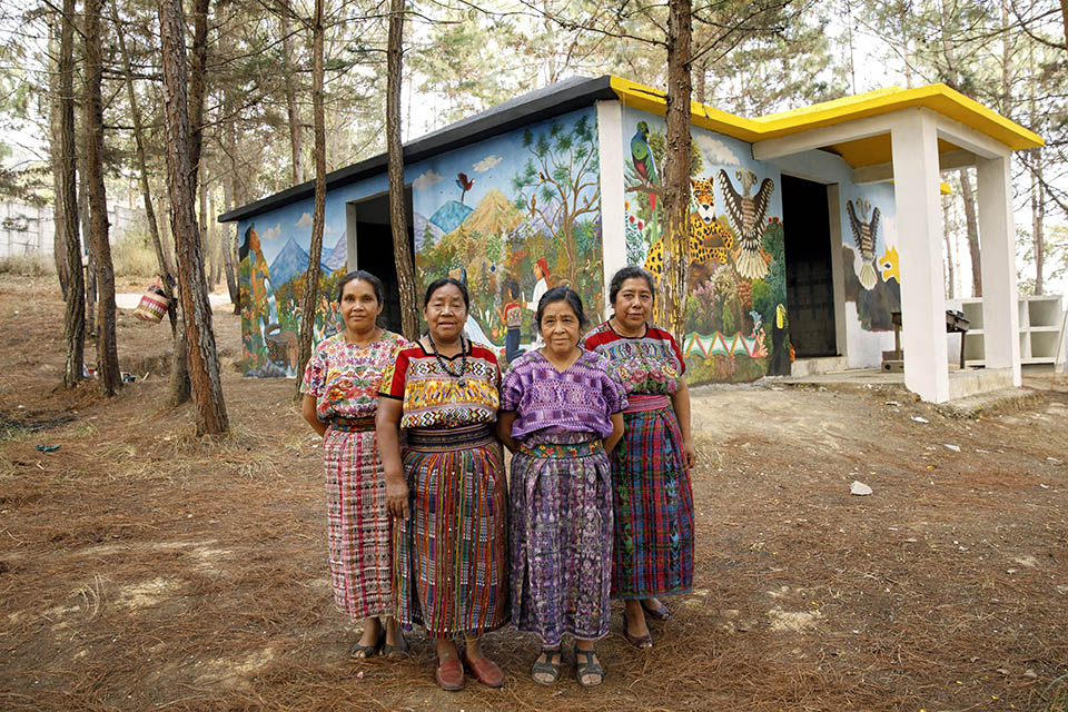 Artists pause while painting the memorial for victims of the conflict in Comalapa for a photo in front of the memorial. Pictured from left to right: María Nicolasa Chex, Rosalina Tuyuc Velásquez, Paula Nicho Cumez, and María Elena Curruchiche. Photo: UN Women/Ryan Brown