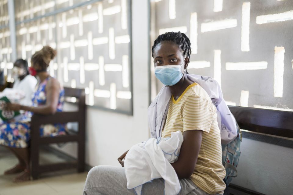 A woman in a healthcare centre wears a mask and practices social distancing. Photo: WHO / Blink Media - Nana Kofi Acquah