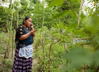 Elena Sam Pec, pictured as she takes a phone call on one phone while checking a text message on another, lives in Puente Viejo, Guatemala, a mostly agrarian indigenous community that relies on wooden canoes to transport their products or to access services. Digital technology can help better connect rural women like Elena with services and resources, but a lack of inclusive design means marginalized groups often stand to benefit least from new innovations. Photo: UN Women/Ryan Brown 