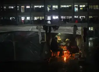 A Palestinian family is seen at a shelter during a rainy night in the city of Rafah, Gaza.