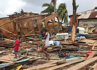 A mother and her children walk through ruined housing in the wake of Hurricane Iota in Puerto Cabezas, Nicaragua. Photo: UNICEF/Inti Ocon/AFP-Services.