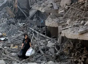 On 29 September 2024 a woman in Beirut, Lebanon walks among the debris of buildings destroyed by airstrikes.