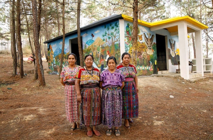Artistas indígenas de San Juan Comalapa, Guatemala, pausan el trabajo de pintura y se toman una foto frente al Centro de la Memoria Histórica de las Mujeres, abril de 2018. En la foto, de izquierda a derecha: María Nicolasa Chex, Rosalina Tuyuc Velásquez, Paula Nicho Cumez, y María Elena Curruchiche. Foto: ONU Mujeres/Ryan Brown.