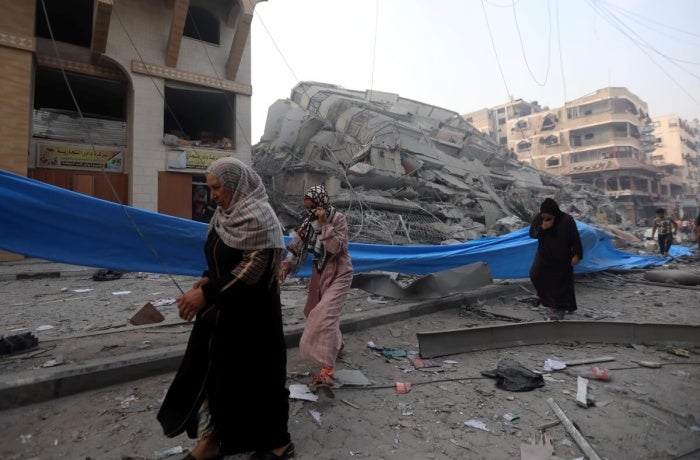 Women are seen in the Nasr neighbourhood of Gaza City on 7 October 2023 after their home was destroyed.