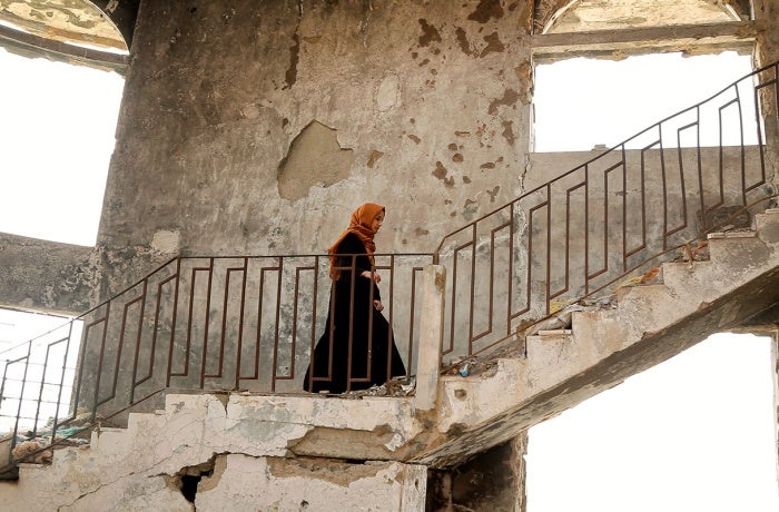A women walks amid ruins in Yemen. UN Photo/Heba Naji