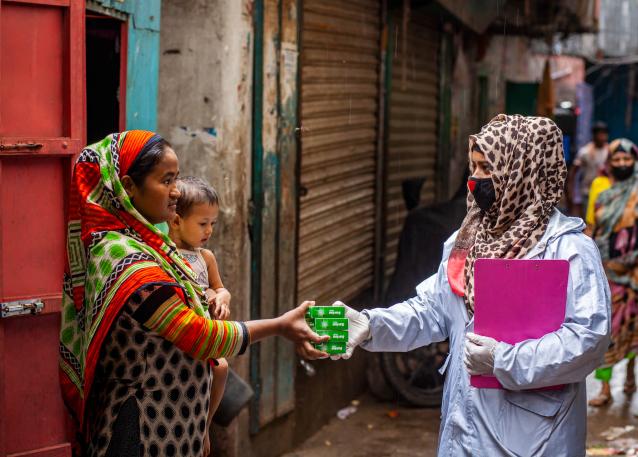 Tanzima Akter works as a community facilitator under the LIUPC project of UNDP Bangladesh. Here she is distributing anti-bacterial and disinfecting soap to a family in Dhaka. Photo: UN Women/Fahad Abdullah Kaizer