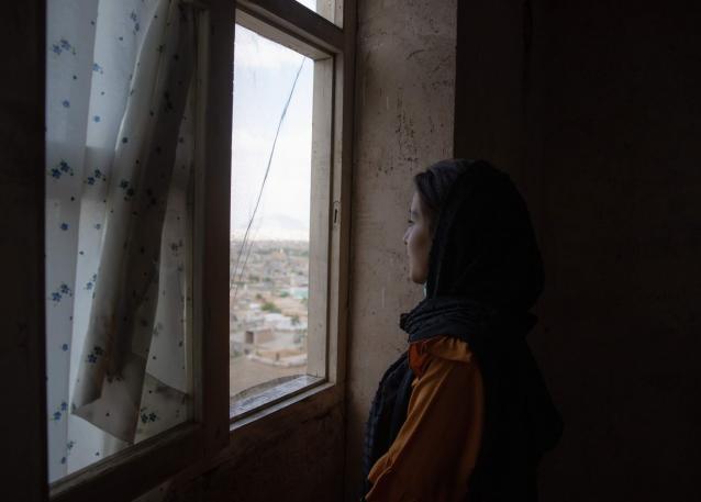 Photo of an Afghan woman looking out her window, for the “After August” in focus package. Photo: UN Women/Habib Sayed Bidell.
