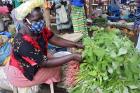Agnes, a vendor at Masiya Market in Yambio, South Sudan, sells vegetables while wearing a face mask distributed by UN Women.